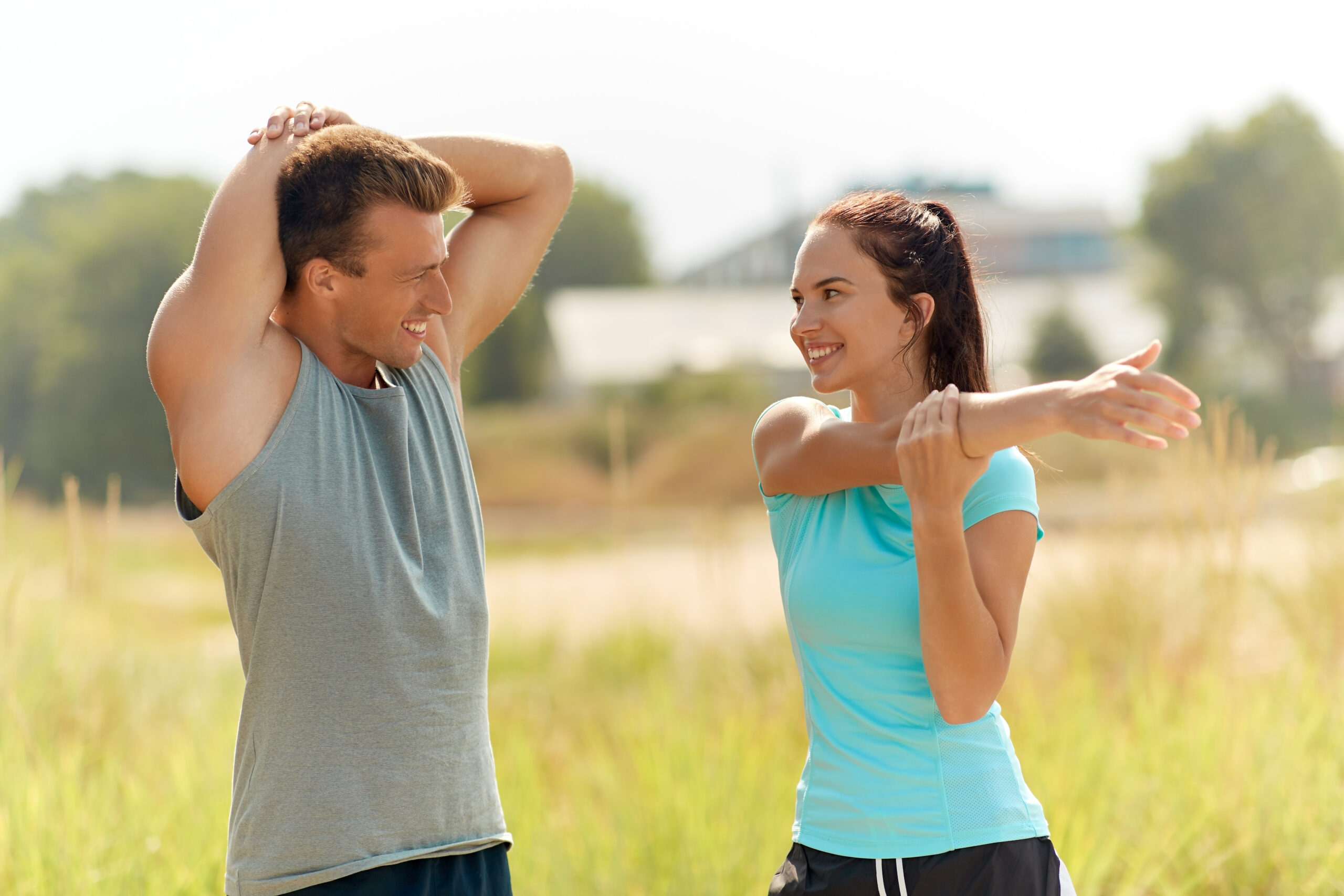 Couple stretching outdoors on a sunny day.