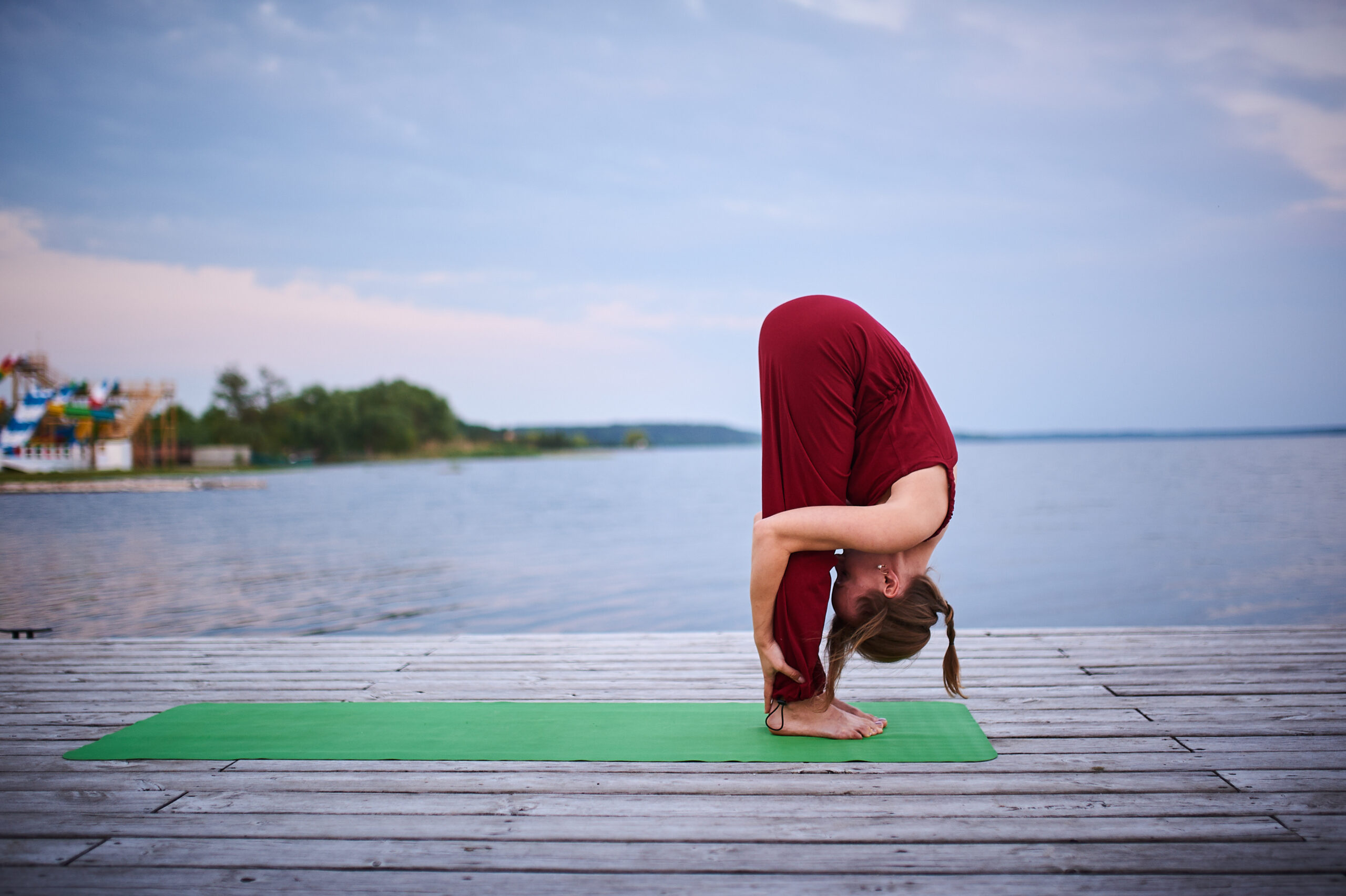 Woman doing yoga forward bend by lake