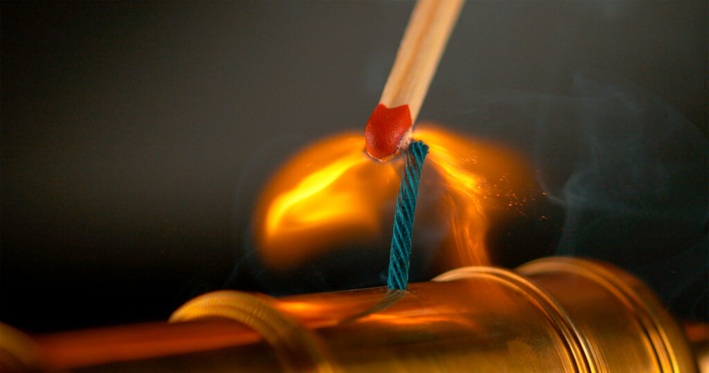Match lighting a blue fuse for cannon ignition.