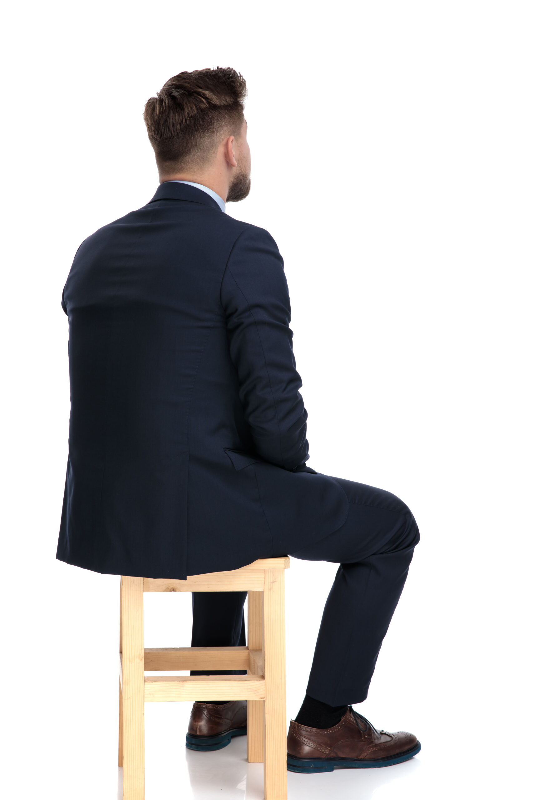 Man in suit sitting on wooden stool, back view