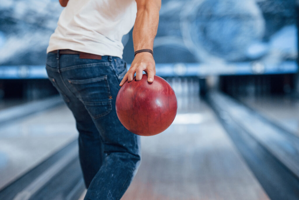 Person bowling with red ball in alley
