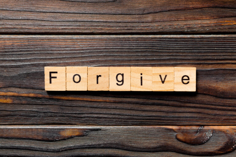 Scrabble tiles spelling 'Forgive' on wooden background.