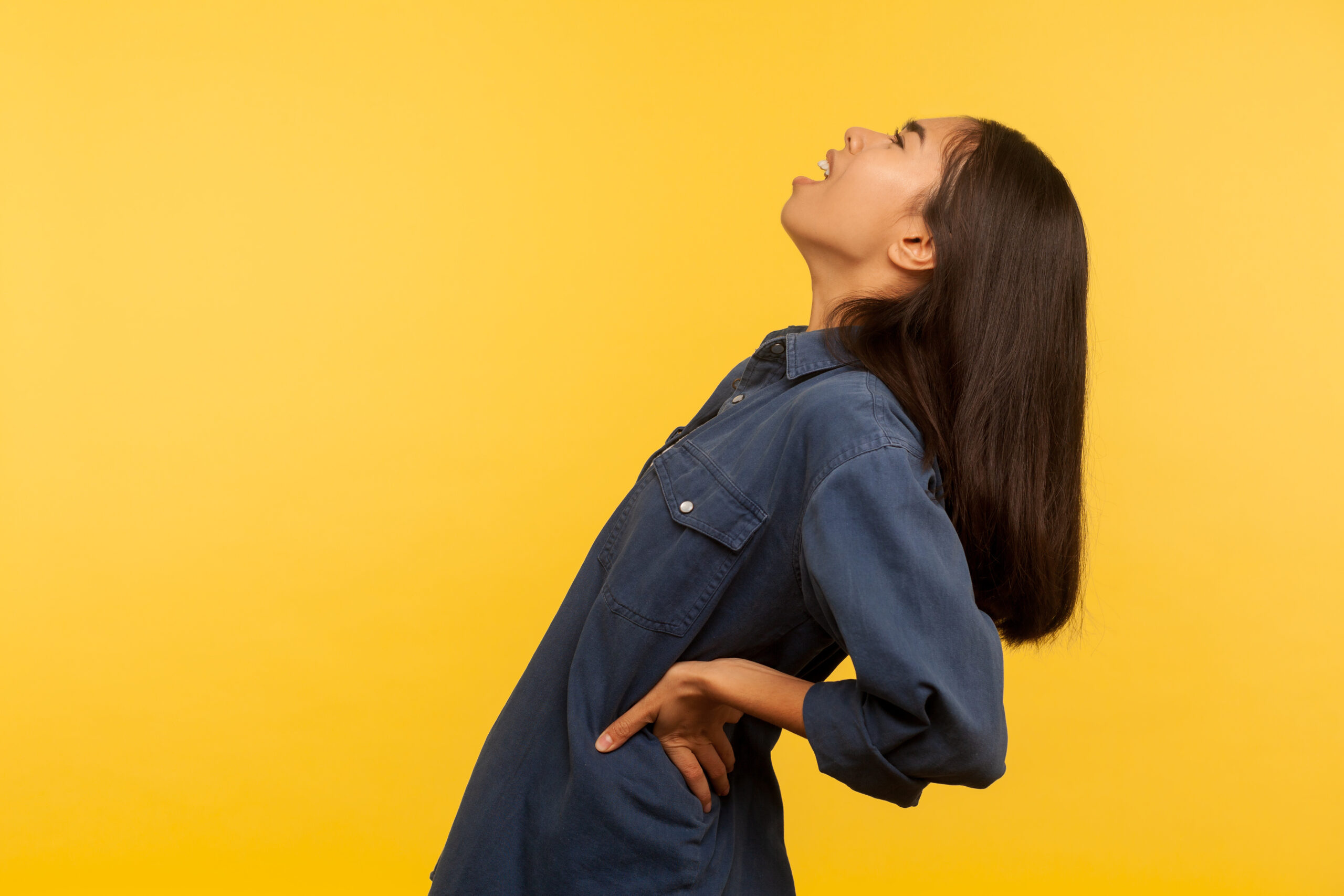 Woman with back pain on yellow background