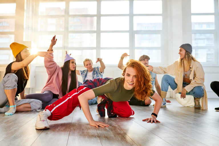 Group breakdancing in a sunlit studio.