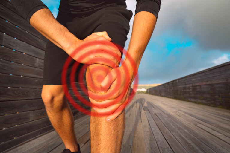 Person holding painful knee during outdoor activity