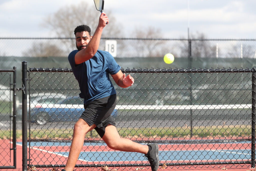 Man playing tennis, hitting ball on court