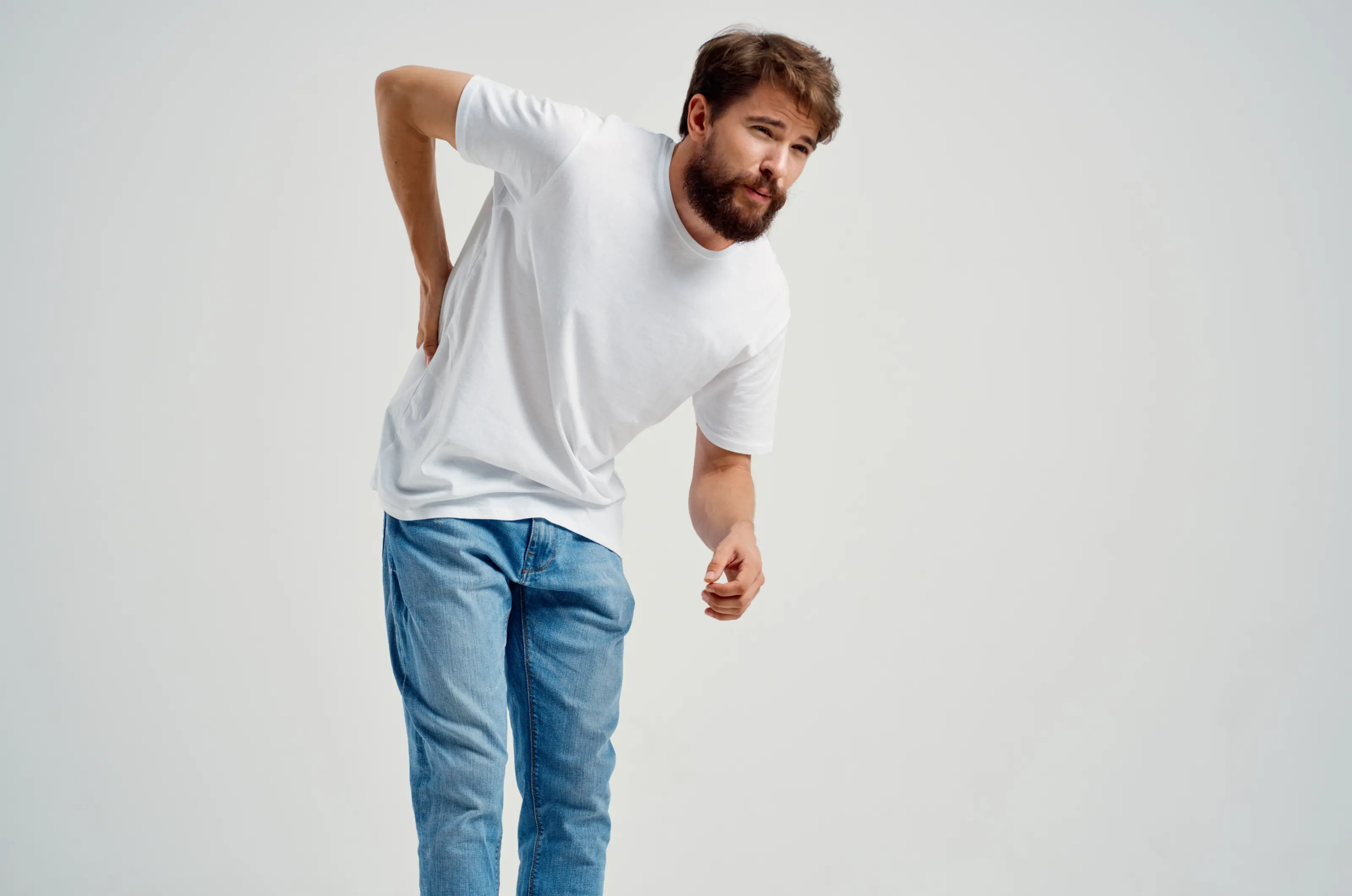 Man with back pain, wearing white shirt, jeans.
