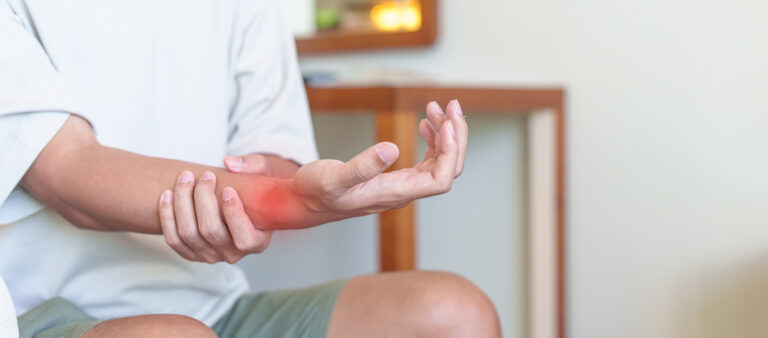 Person holding painful, inflamed wrist.
