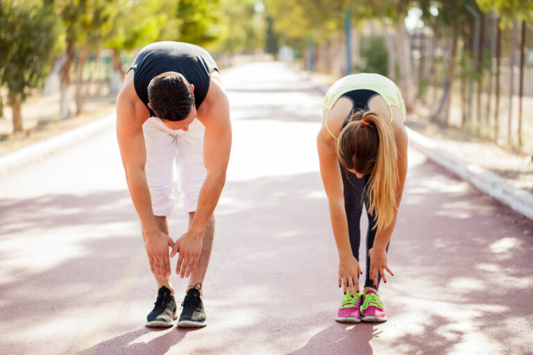 Two people stretching on outdoor path.