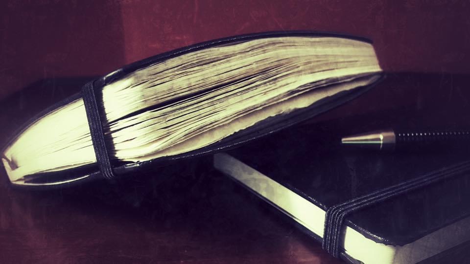 Old journal with black pen and notebook