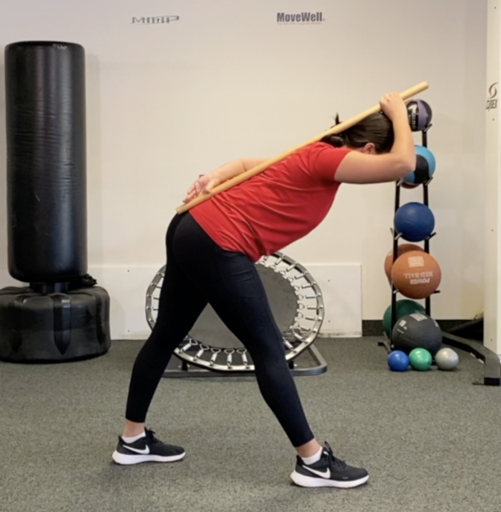 Person doing stick mobility exercise in gym.