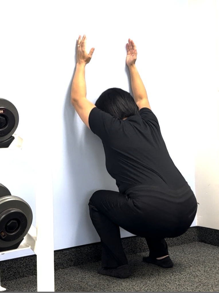 Person stretching arms against wall for exercise
