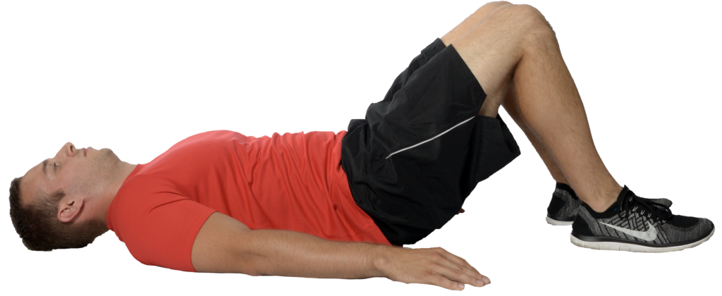Man performing glute bridge exercise on floor.