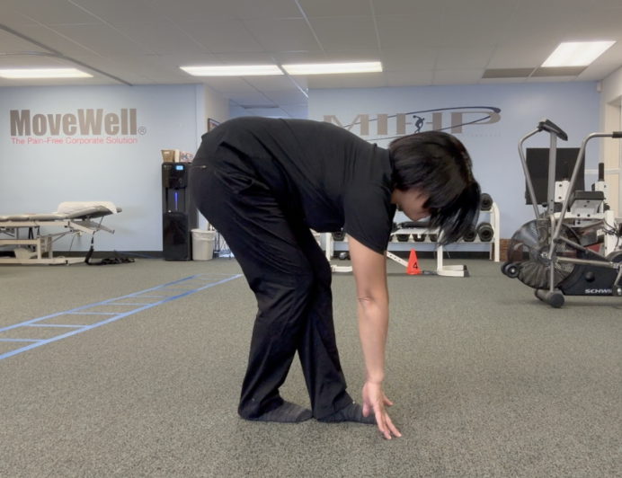 Person stretching, touching toes in exercise room.