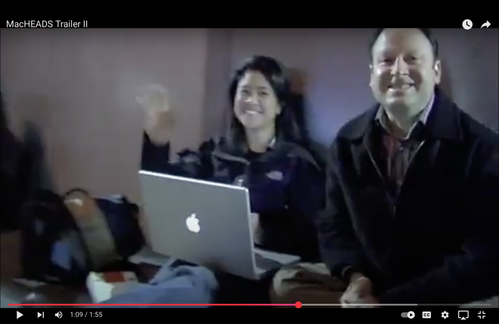Two people smiling near a laptop.