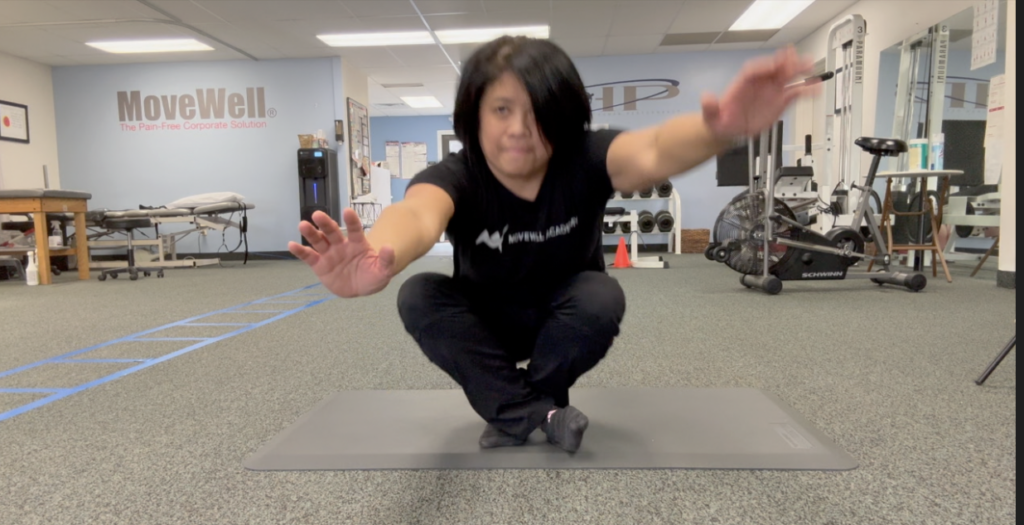 Person balancing on mat in gym setting.
